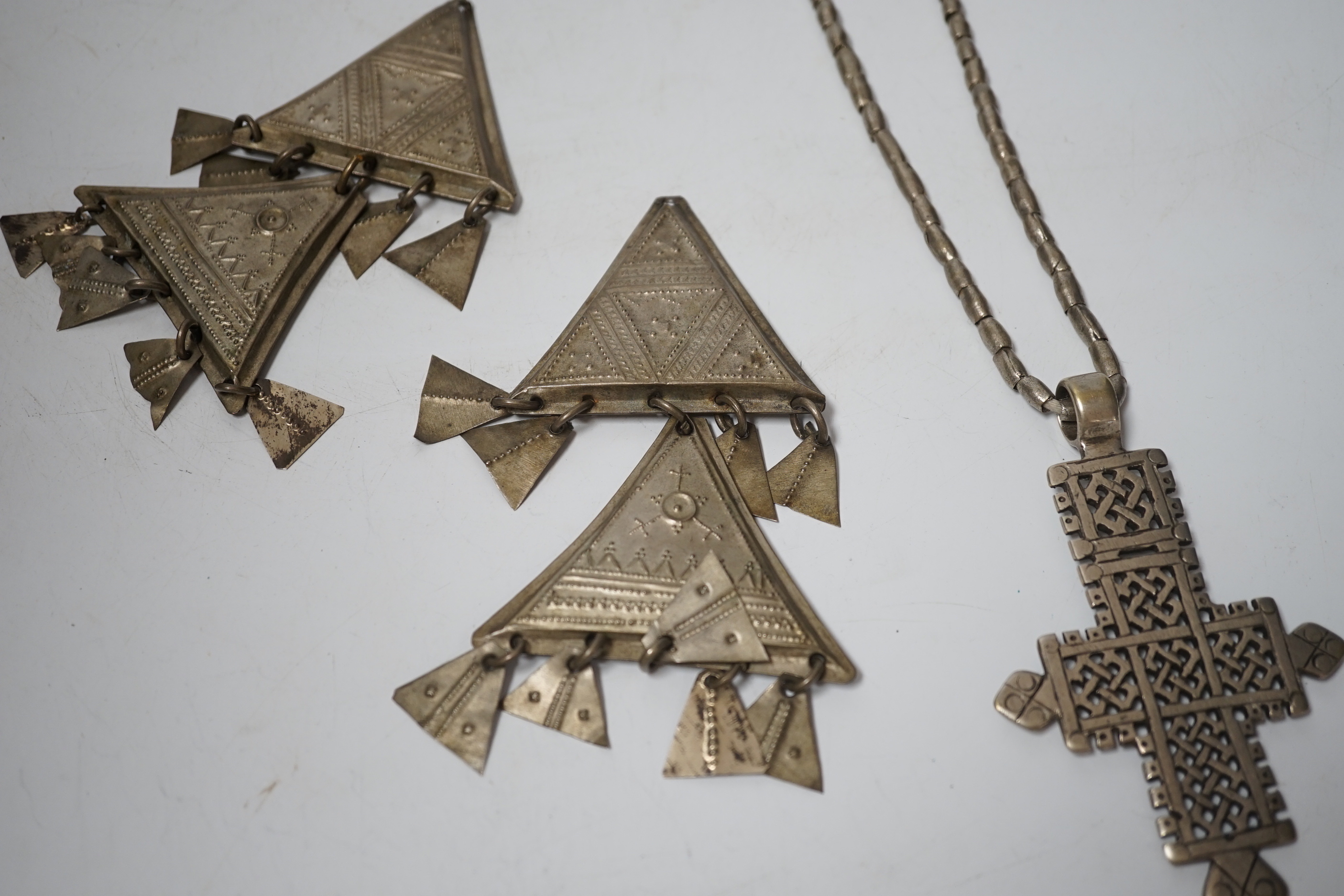 An Ethiopian white metal cross pendant necklace, overall 90cm, together with a pair of Tuareg silvered metal drop earrings (lacking hooks), approx. 12cm.